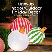 Inflatable holiday ornaments in red, white, green, and orange on a wooden surface outdoors.